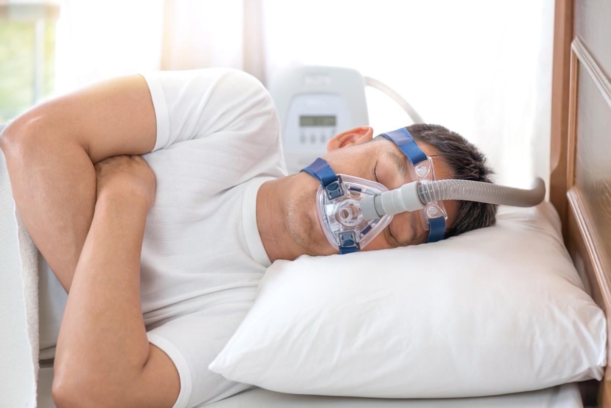 Μάσκα CPAP στο πρόσωπο ενός άνδρα με άπνοια ύπνου